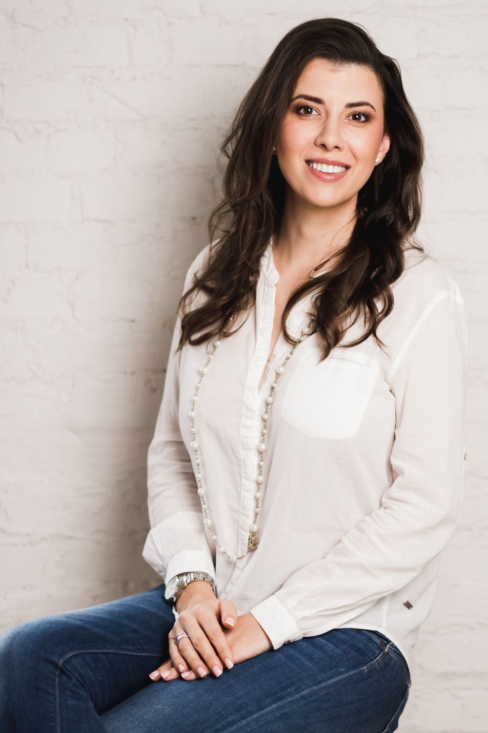 Professional portrait of woman in white button-up shirt and jeans.