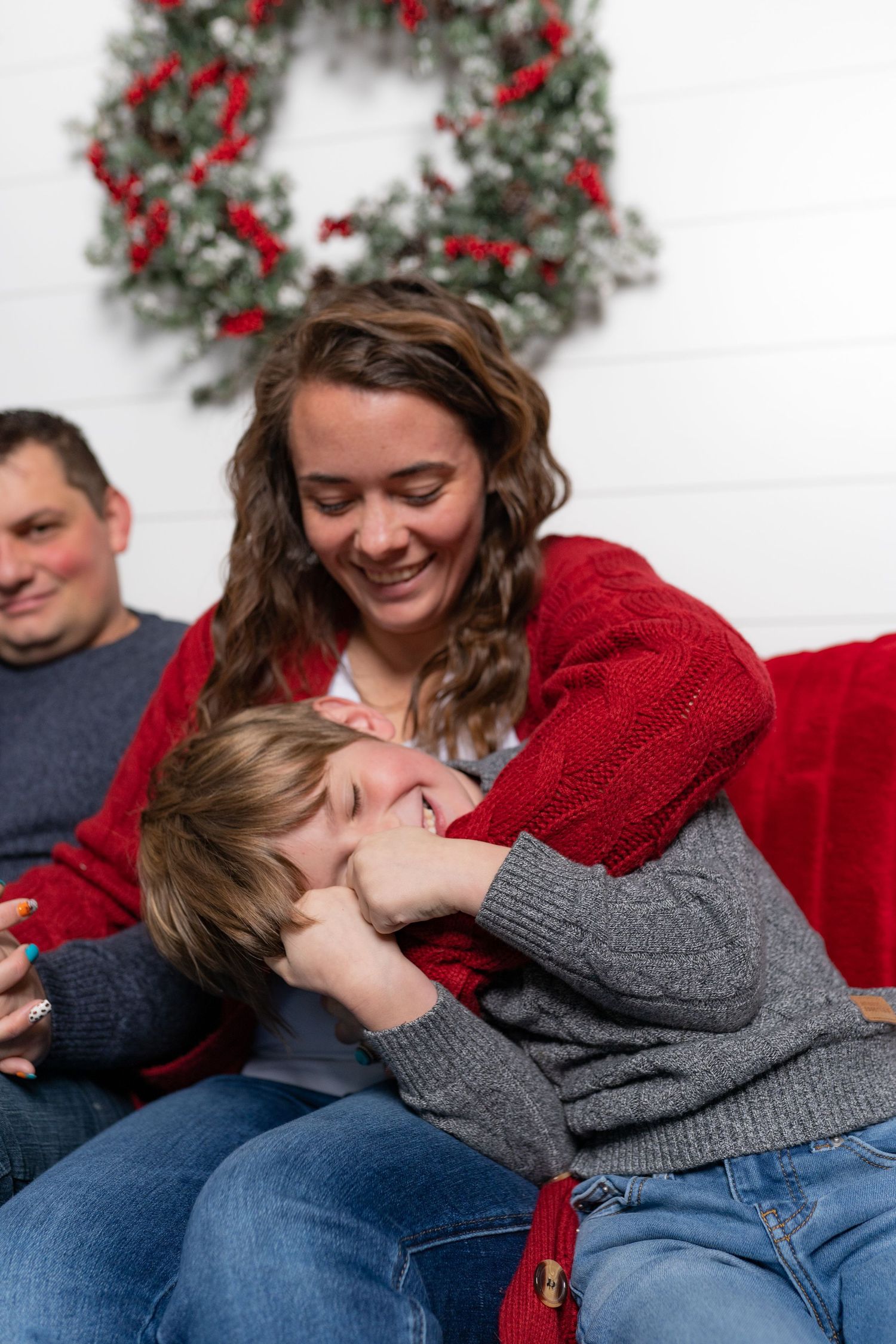 Cozy holiday scene with festive wreath and red decor on white wall.