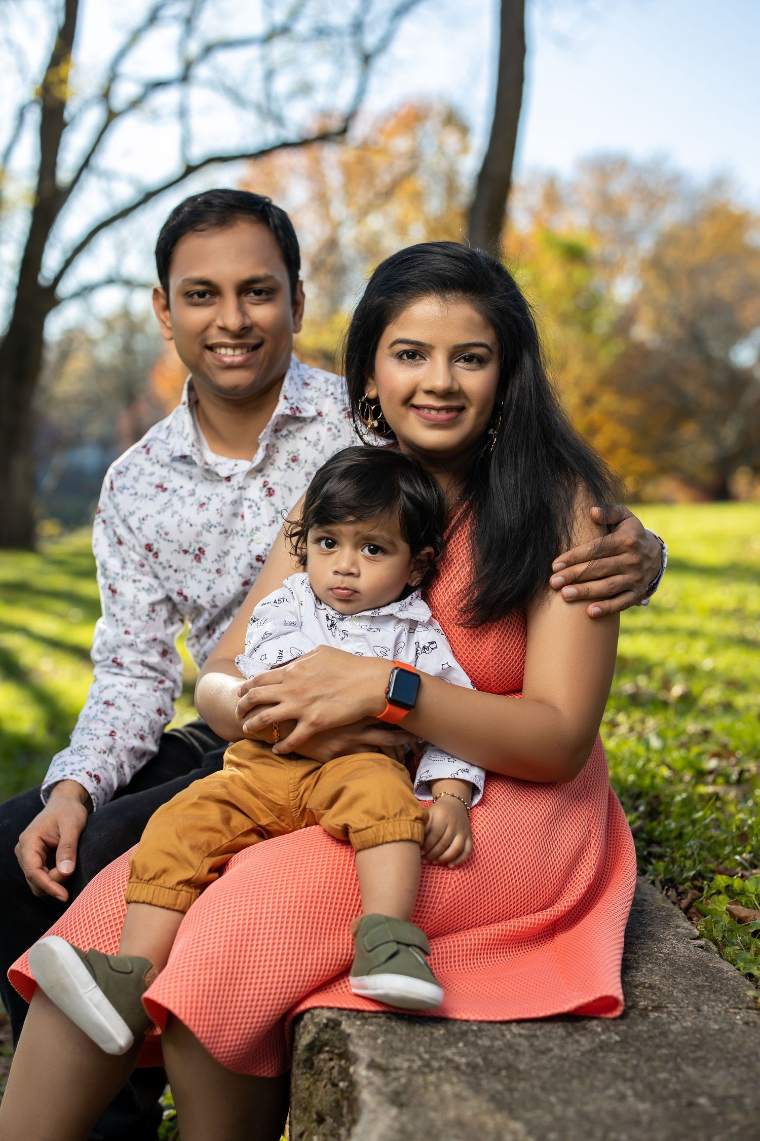 Young family in coordinated outfits poses together outdoors during autumn season.