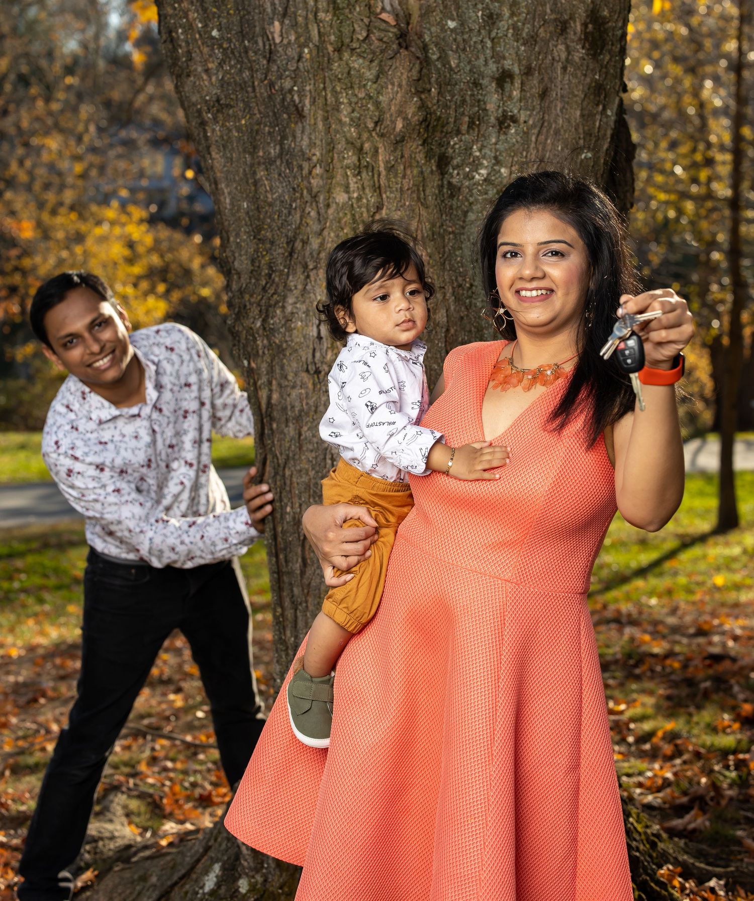 Playful family portrait in autumn park with fall foliage backdrop.