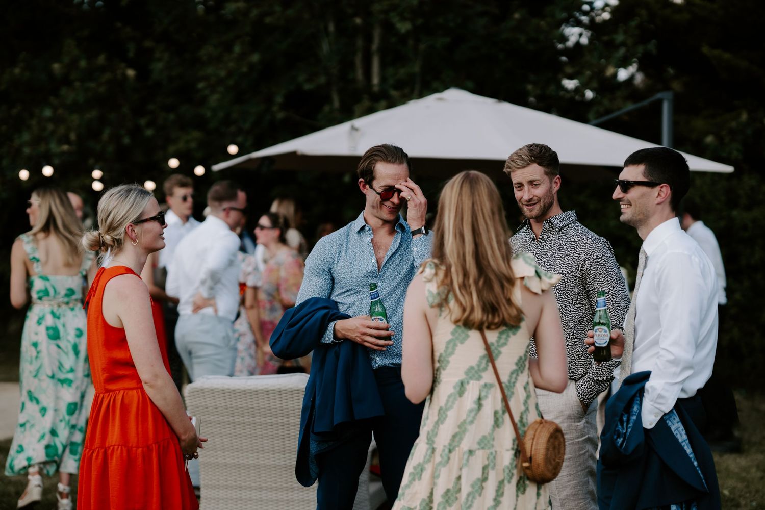 wedding guests talking and laughing with each other on lawn in islip, Oxfordshire
