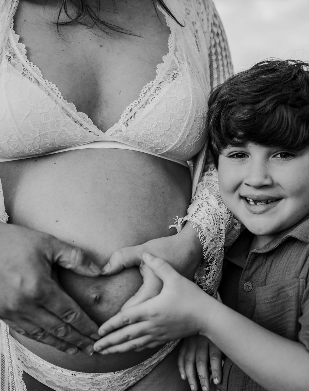 A black and white intimate maternity photo showing gentle hands on a growing belly.