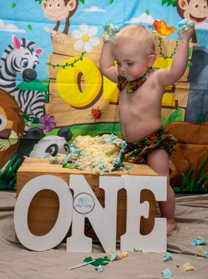 A baby smashing a cake with a jungle theme