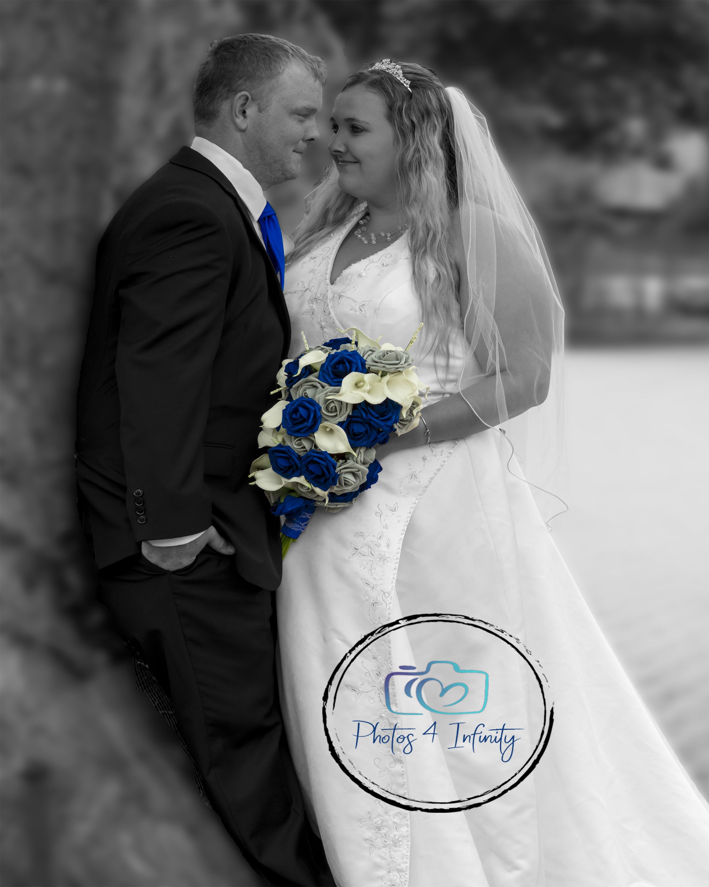 A bride and groom looking at each other leaning against a tree