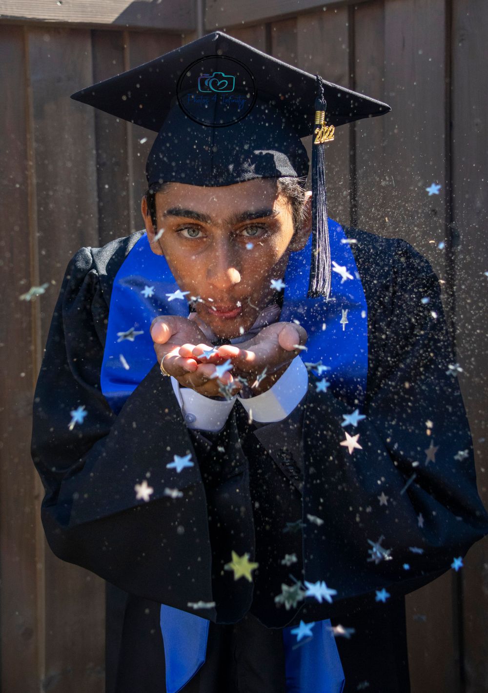 A young man graduating blowing confetti towards the photographer