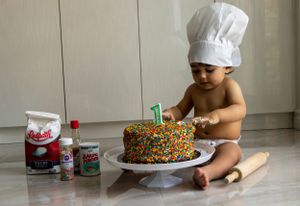 A baby in a chefs hat playing with a decorated cake