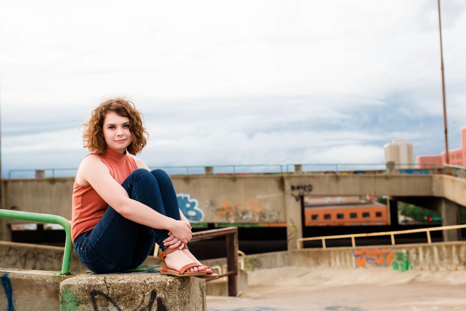 Person sitting on urban rooftop with industrial cityscape in background.