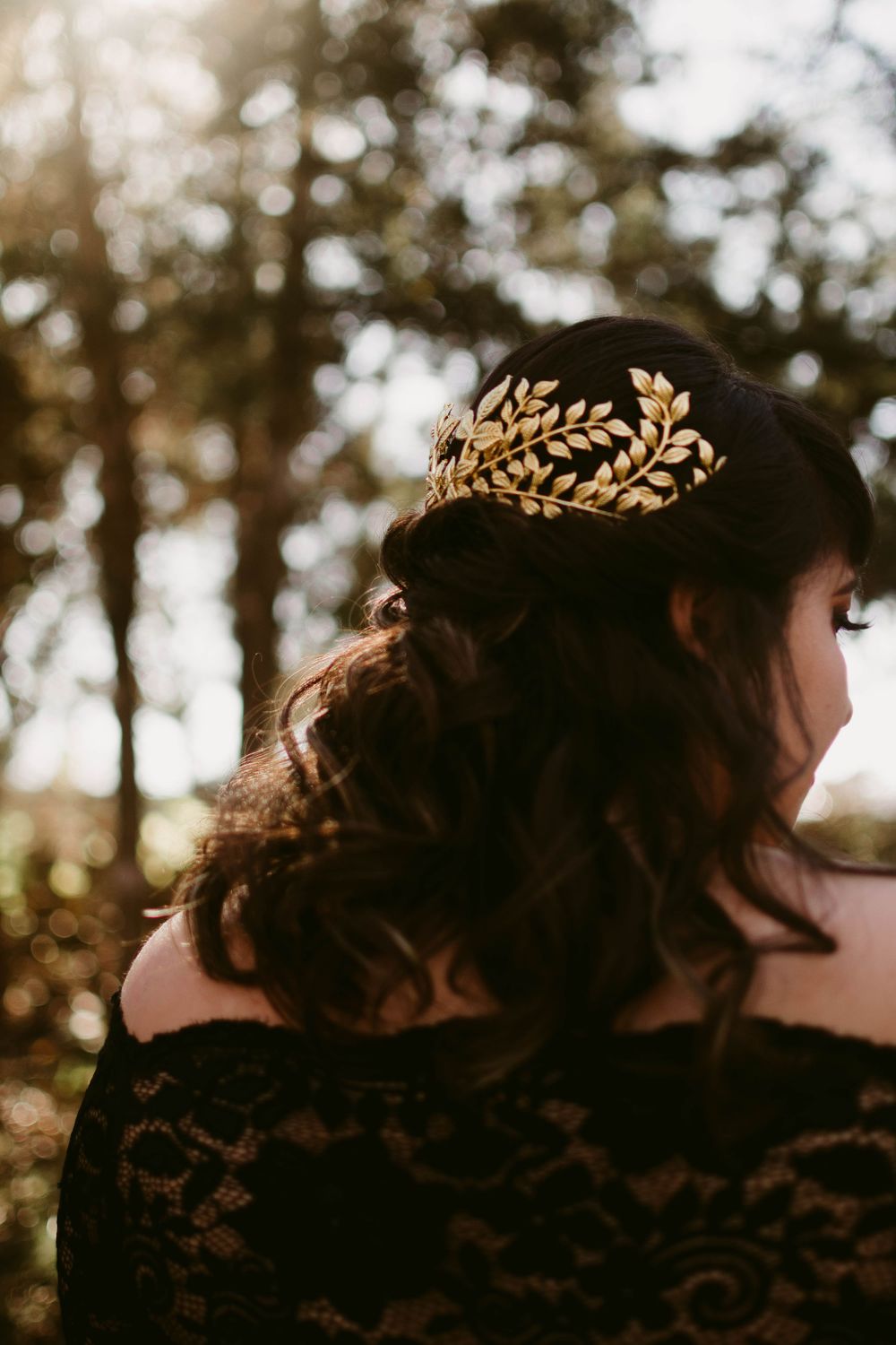 Back view of ornate gold leaf crown hair accessory against autumn trees.