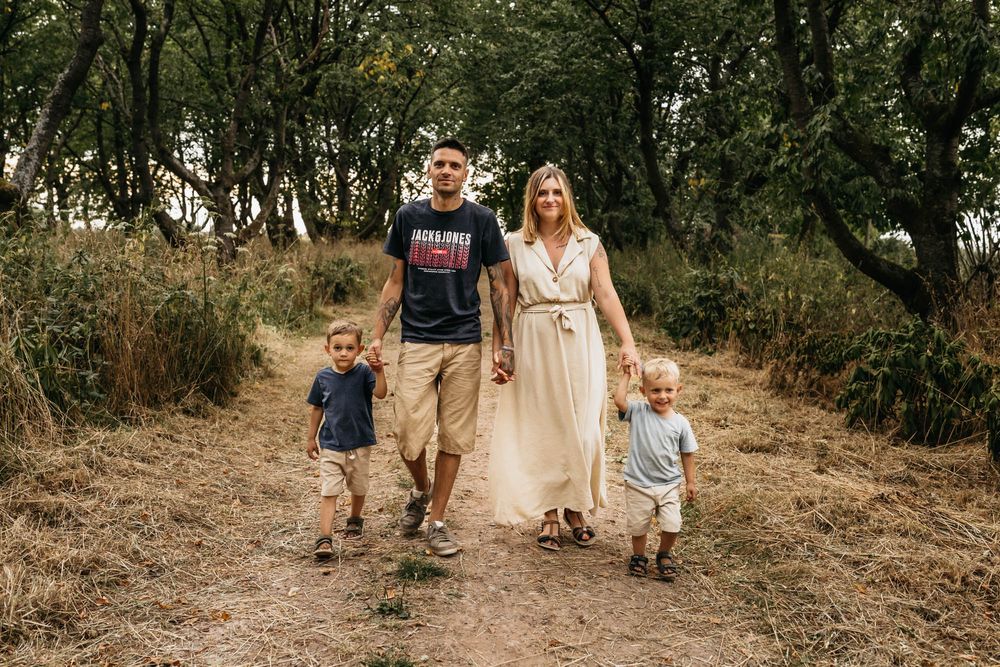 Family walking together on a nature trail through tall grass and trees.