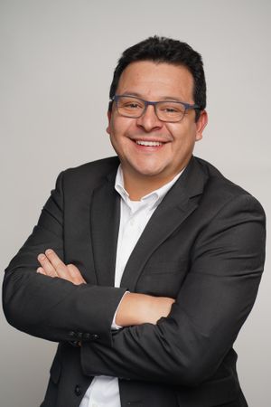 Professional headshot of someone in business attire with glasses and a warm smile.