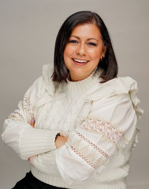 Professional headshot of someone wearing a cozy white knit sweater with lace details.