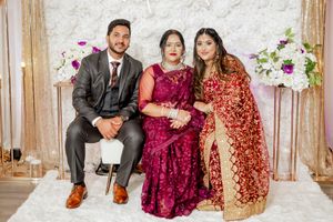 Family portrait featuring three people in formal attire against floral backdrop.