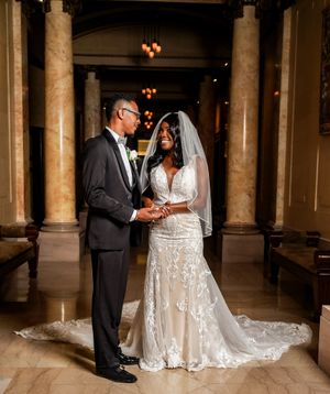 Elegant wedding ceremony photo in venue with marble columns and warm lighting.