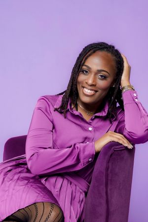 Portrait against purple background featuring bright fashion and joyful expression.