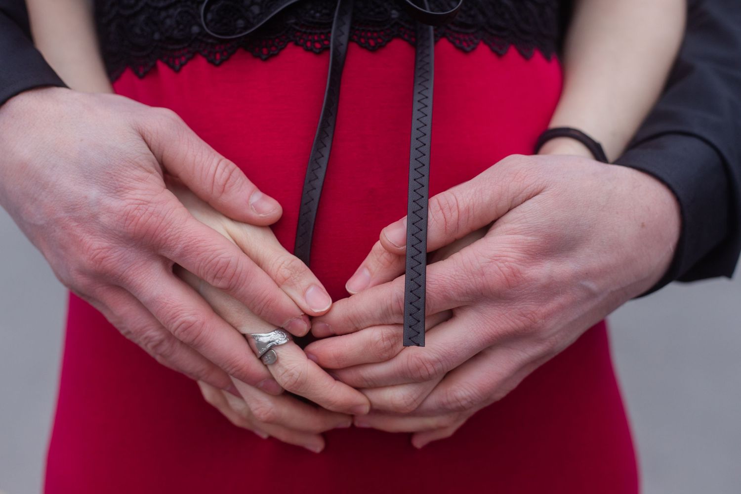 Close-up of hands showing wedding rings against a red dress.