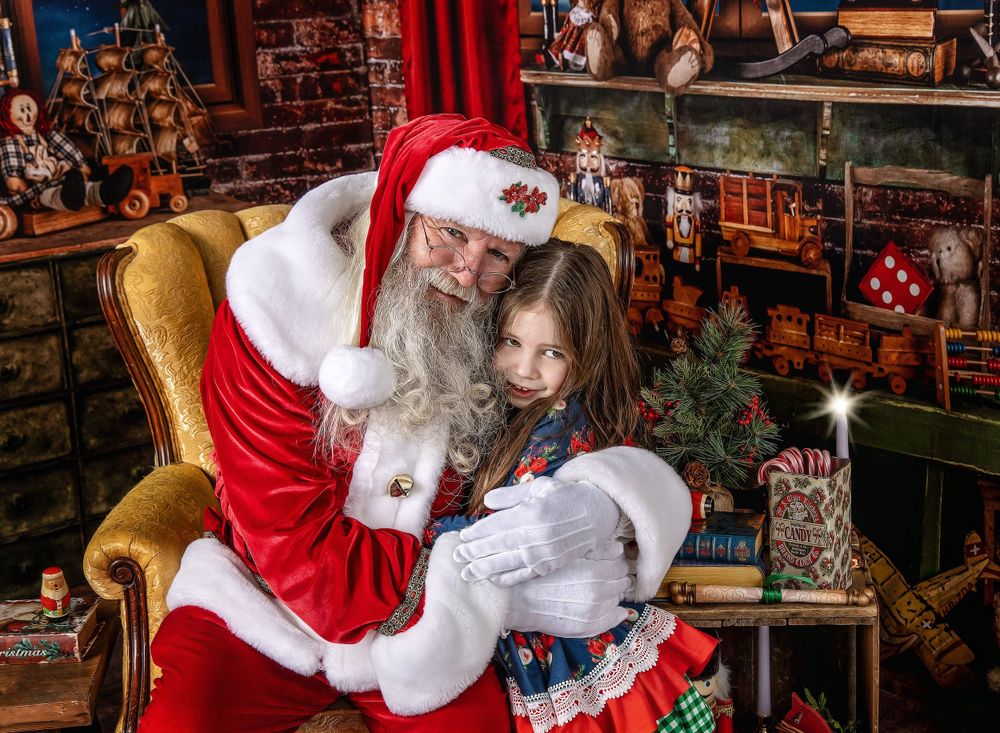 Santa kneeling beside child during holiday portrait session in festive Austin studio set