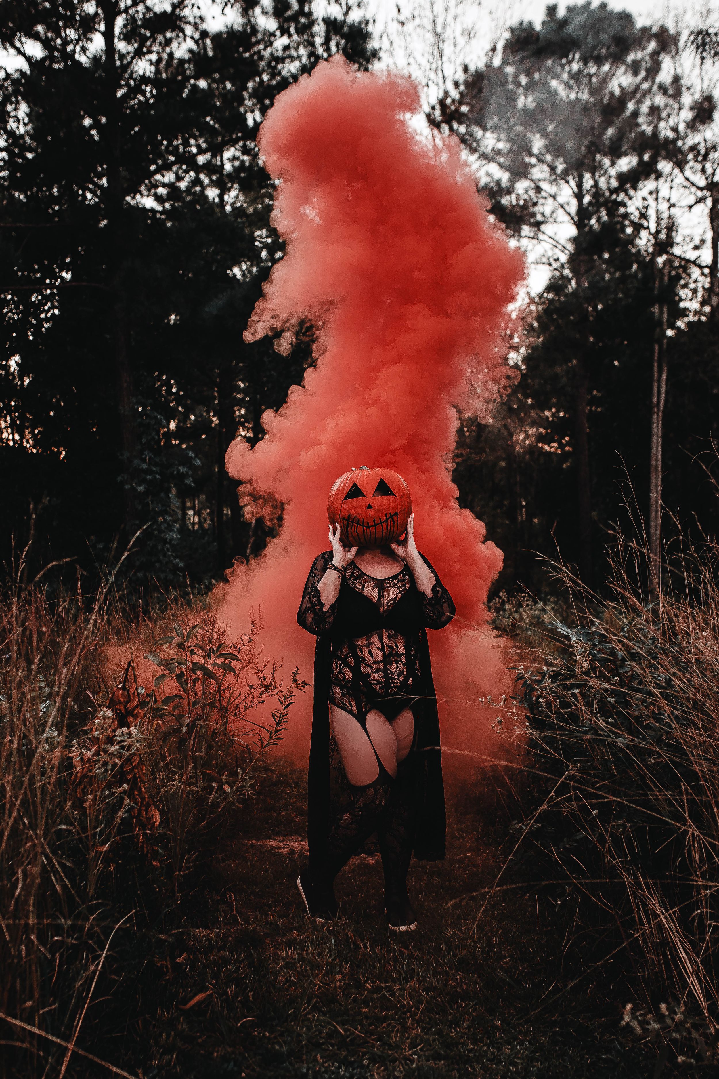 Atmospheric Halloween scene with a pumpkin mask and red smoke bomb in a moody forest setting. spooky, horror, pumpkin