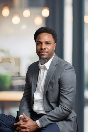 Professional headshot in modern office setting with bokeh lights and clean background.