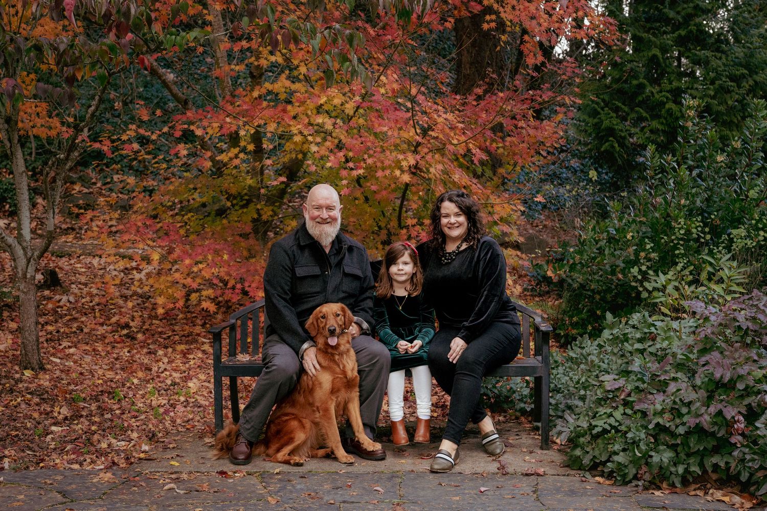 Family portrait of parents and a child with golden retriever under vibrant autumn leaves, Pacific Northwest park session.