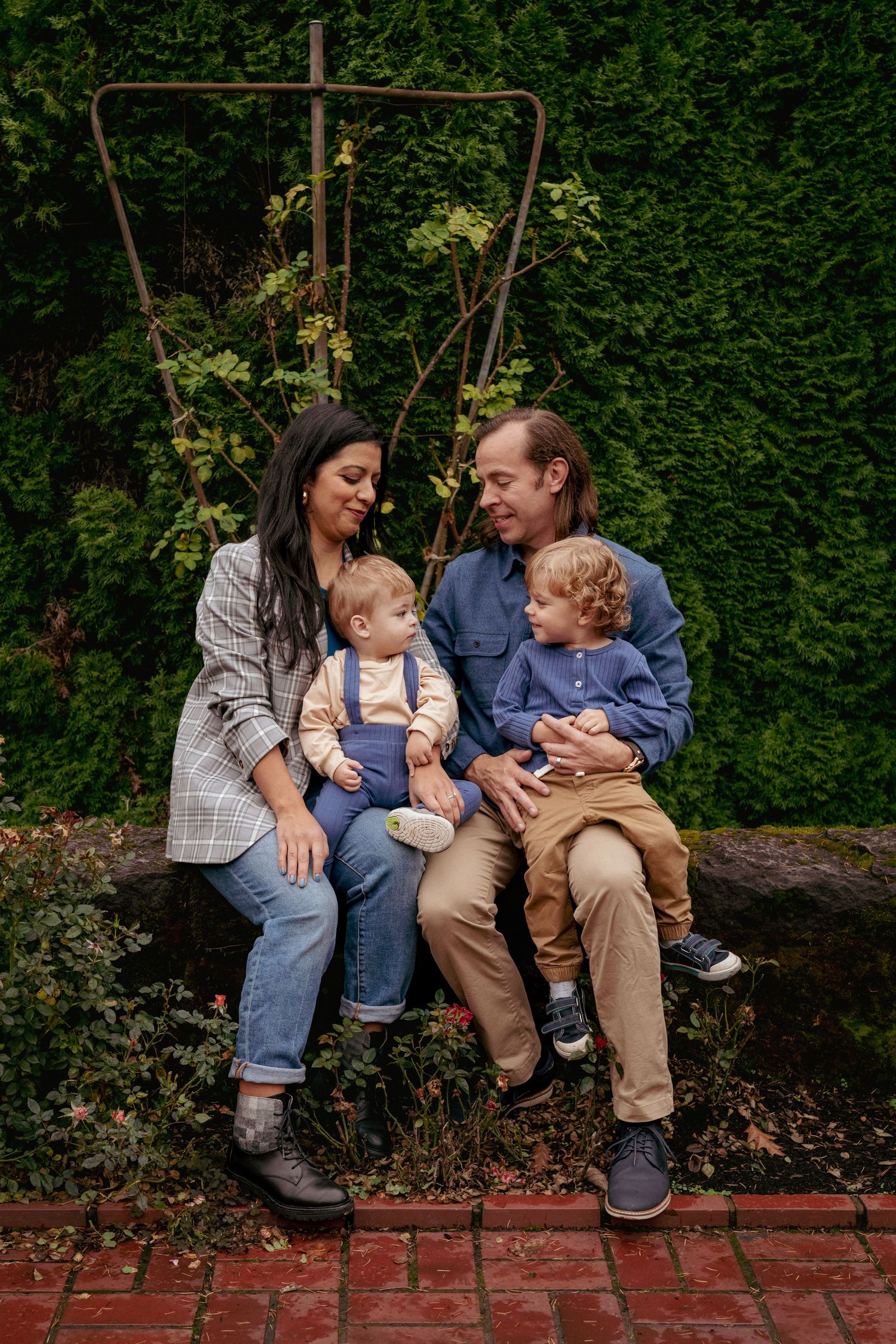 Mother and father with toddler and baby on park bench, fall lifestyle session in Rose Garden Portland.