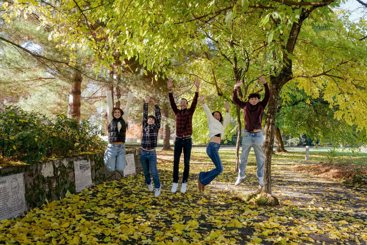 Fun family moment jumping in yellow leaves, Portland Oregon family photography, PNW autumn portraits.