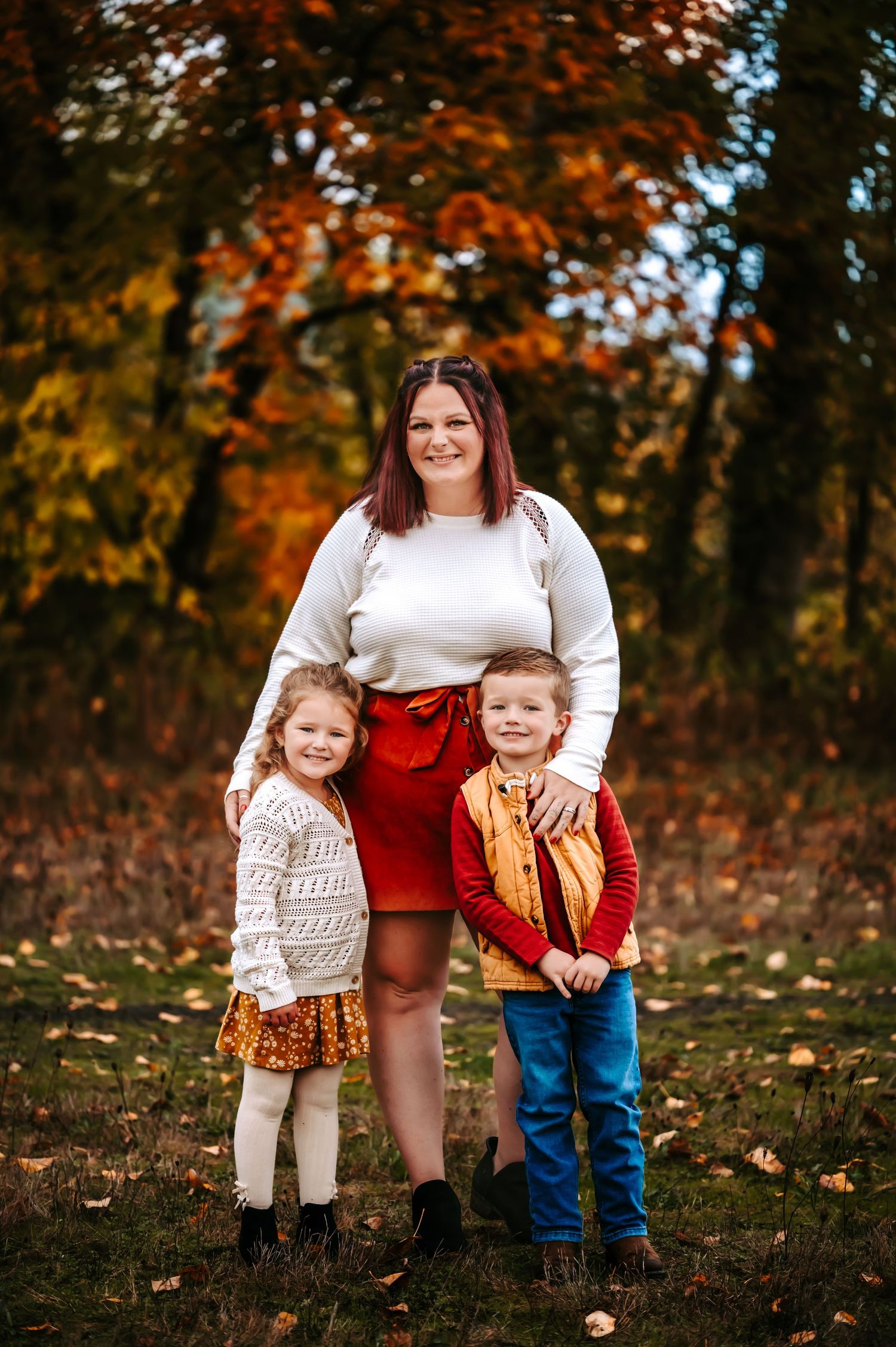 Family group poses together in autumn setting wearing coordinated outfits.
