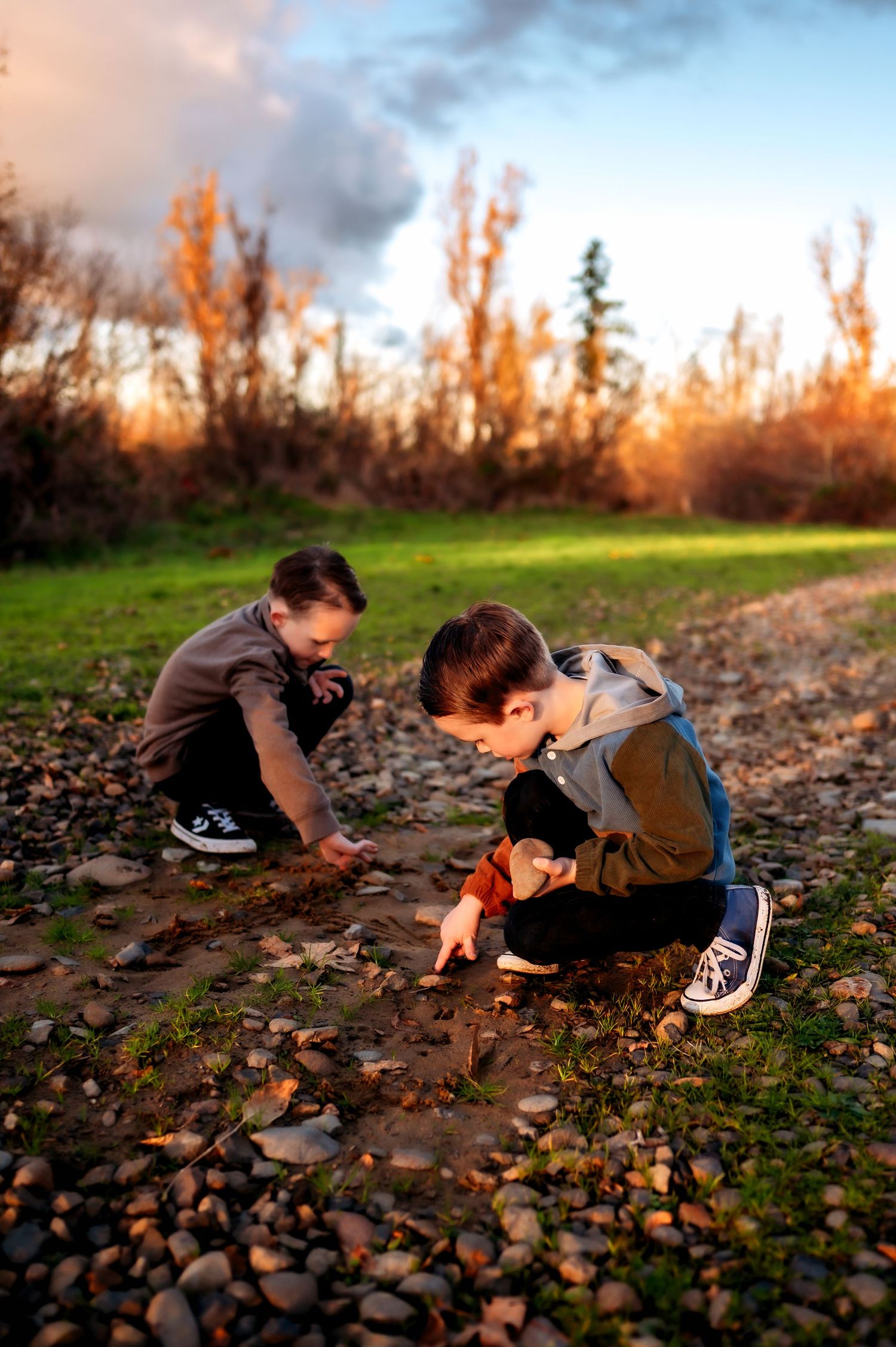 Children playing and exploring in rocky terrain during golden sunset.