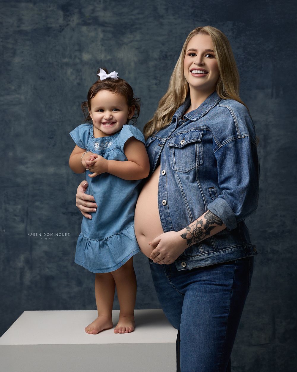 Studio portrait featuring denim-clad duo in casual style against textured background.