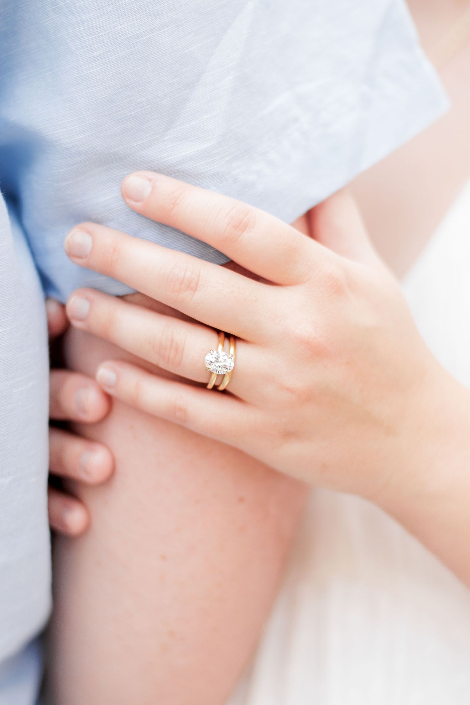 A diamond engagement ring and wedding band set on the bride's hand as she holds her husband hand