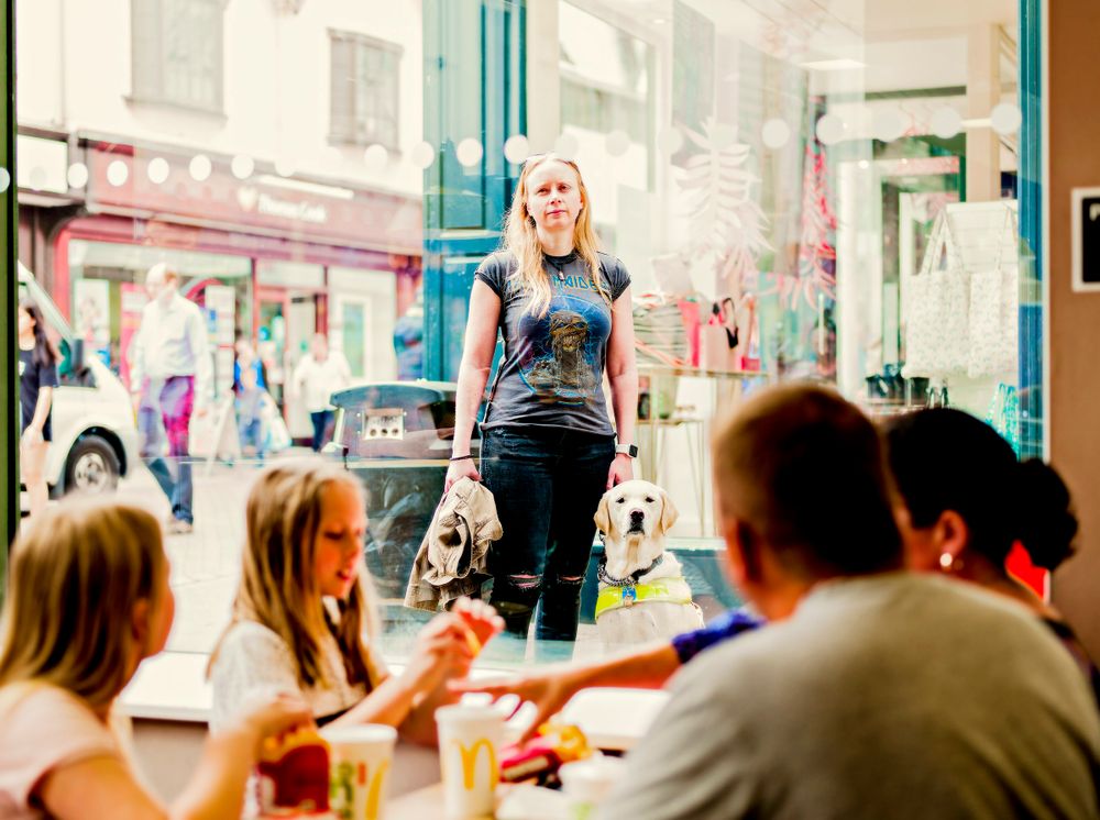 People dining at a restaurant with street view through large windows.