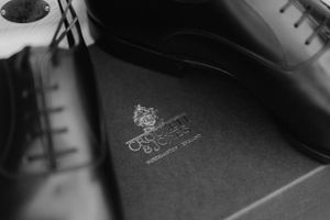 Close-up black and white photo of an embossed logo on dark leather material.