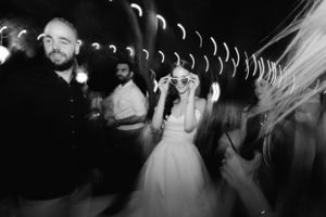 Black and white motion blur photo of wedding party dancing at a reception with trailing light effects.