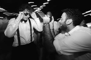 Three people in formal attire dancing and celebrating at a party with dramatic black and white lighting.