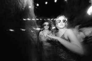A black and white nighttime photograph showing people wearing sunglasses at what appears to be a party or event.