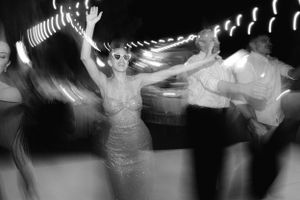 A blurred black and white photo of people dancing at a party with motion trails creating a ghostly effect.