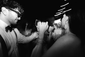 Black and white photo of people dancing and celebrating at a party in a dark room with energetic motion.