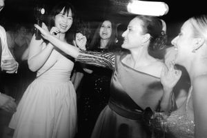 Black and white photo of people dancing and celebrating at a party, with one person holding a plate or tray.