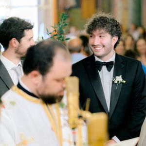 Orthodox wedding ceremony in progress with guests and clergy in traditional attire at an ornate church setting.