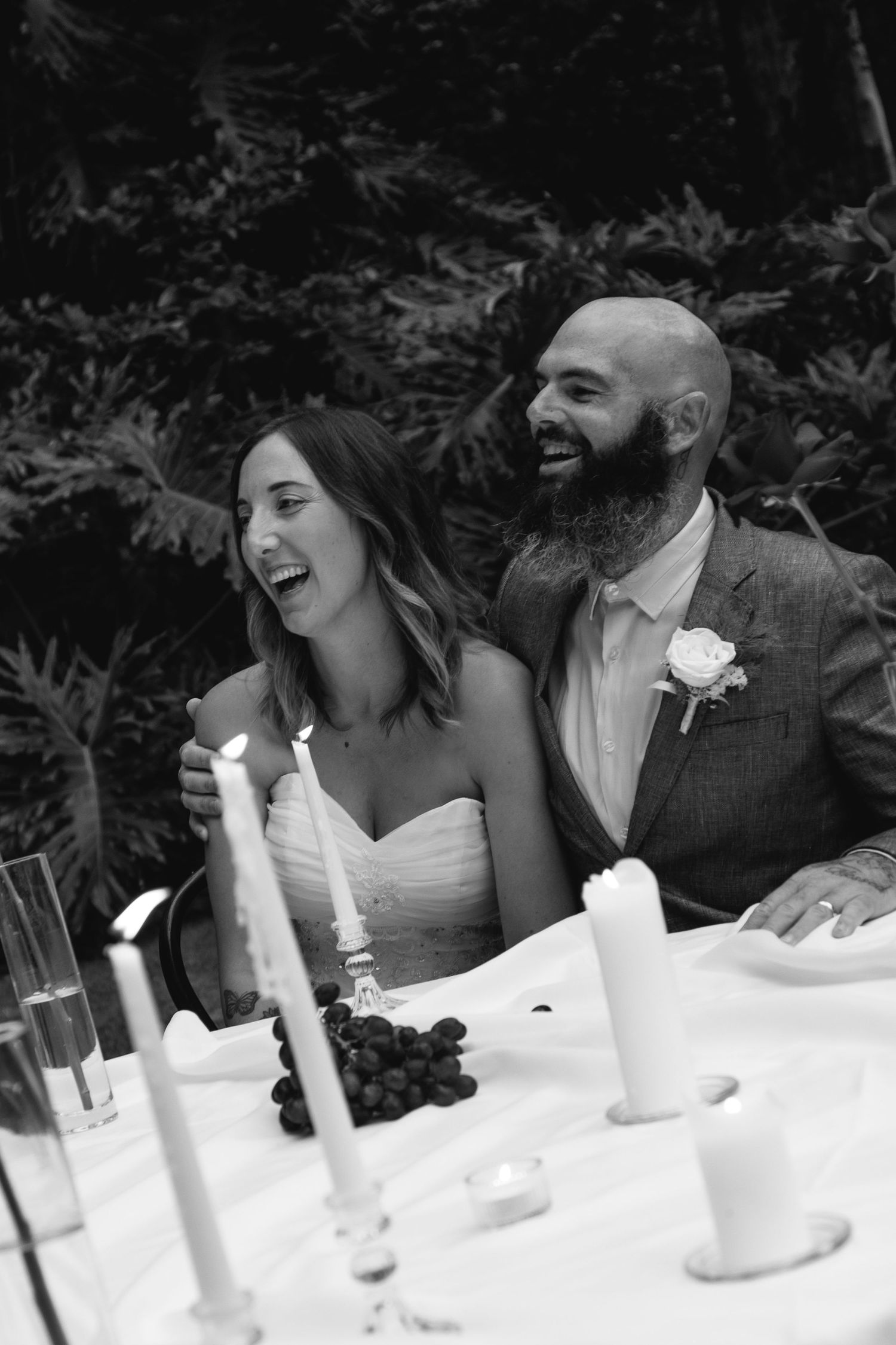 A series of intimate black and white photos showing the head table at a wedding reception with table decor and candles.