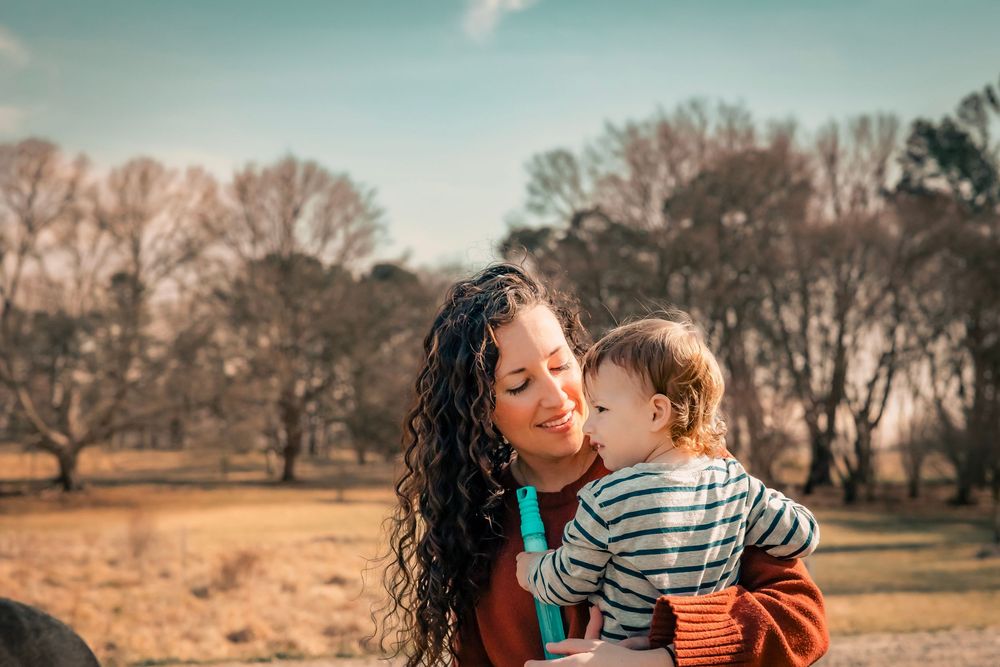 Mother and child share tender moments together in a natural outdoor setting during golden hour.