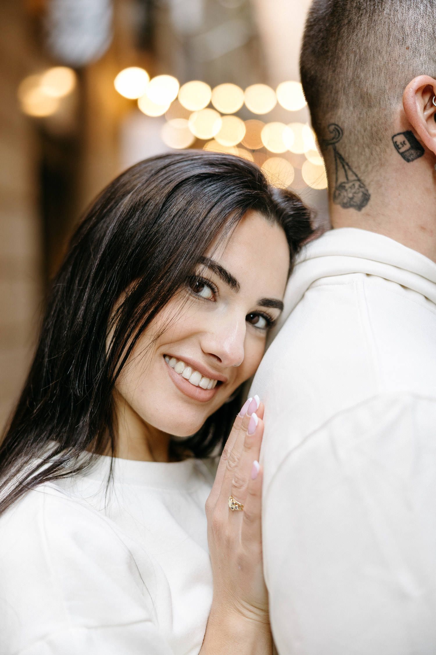 Romantic couple sharing intimate moments in a warmly lit indoor setting wearing matching white outfits.