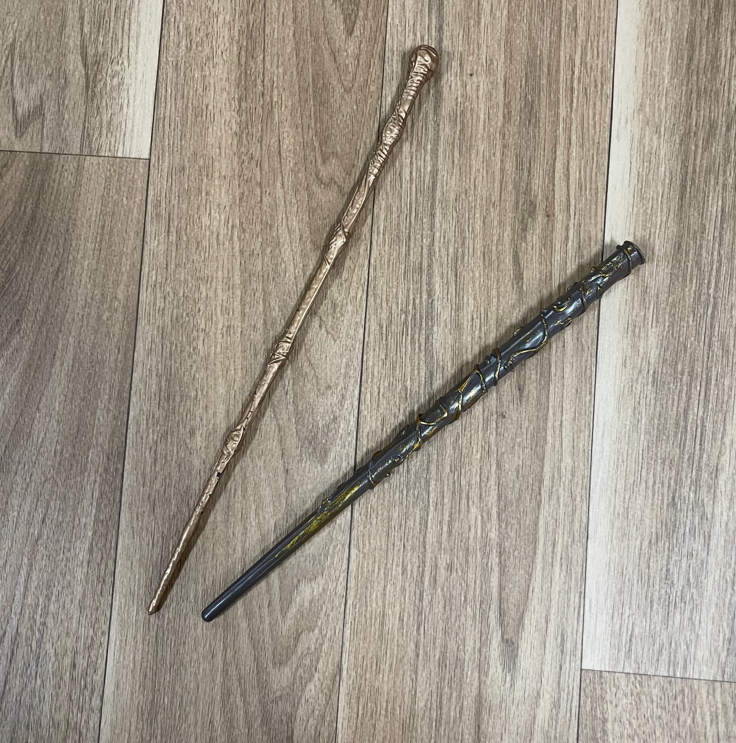 Two decorative wands displayed on a wooden floor surface.