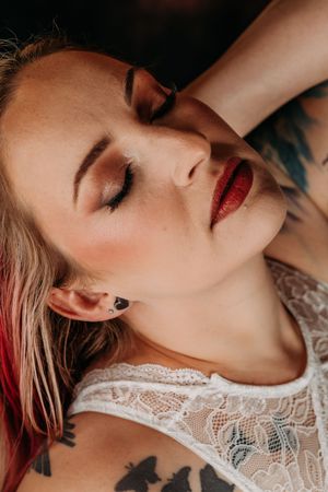 Sensual close-up portrait with red lipstick and white lace detail against moody lighting. Intimate Boudoir Photographer Grand Rapids MI