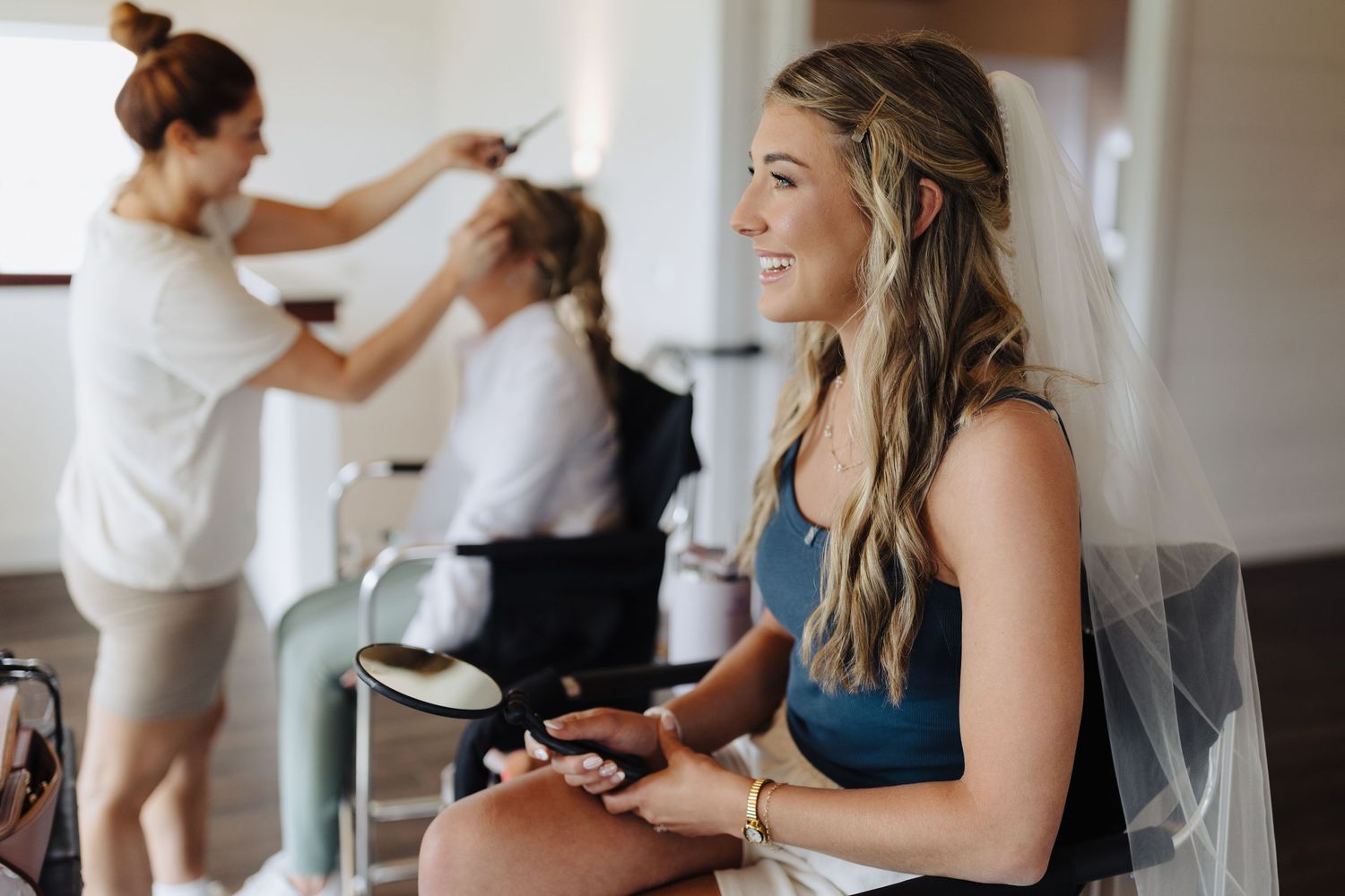 People getting ready in preparation room with hairstyling and beauty services being done before special event.