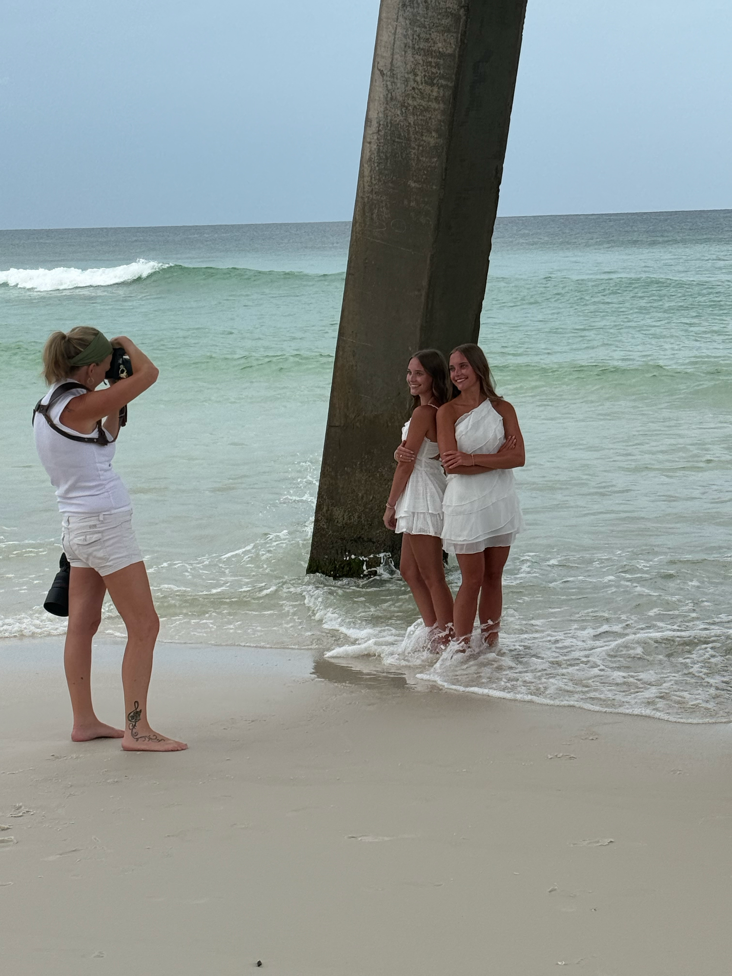 Sequence of connected beach photos showing people playfully posing and interacting under a pier on a sunny day.