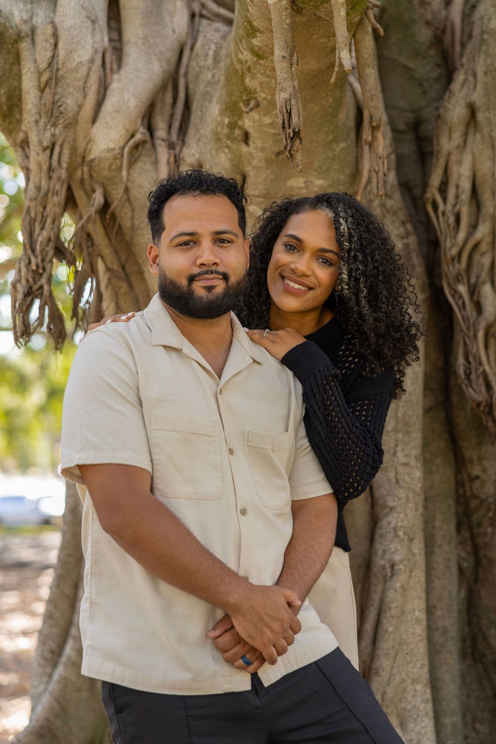 Couple posing together in front of large banyan tree.