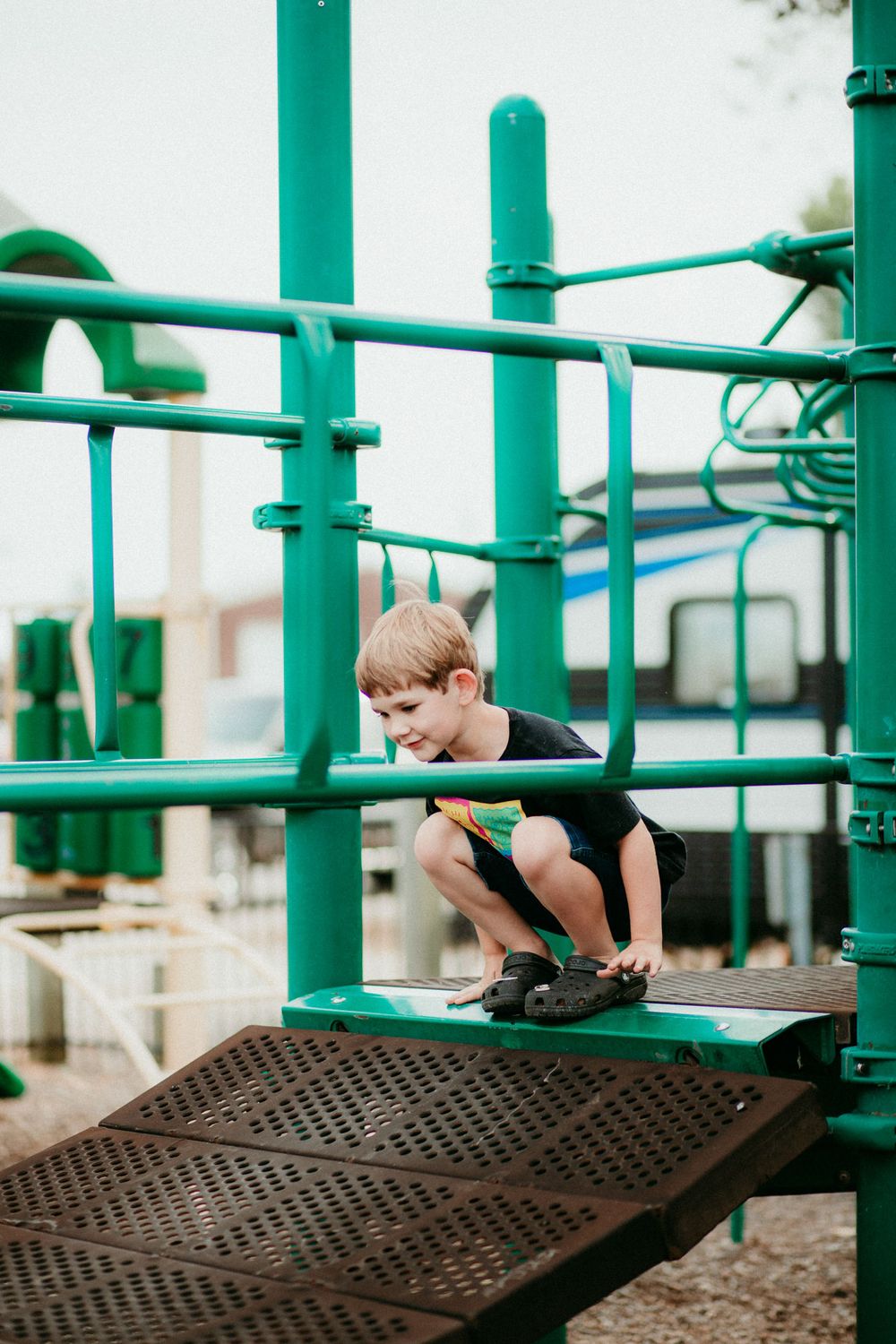 A series of metal playground bars painted in bright turquoise green stand against a light background.