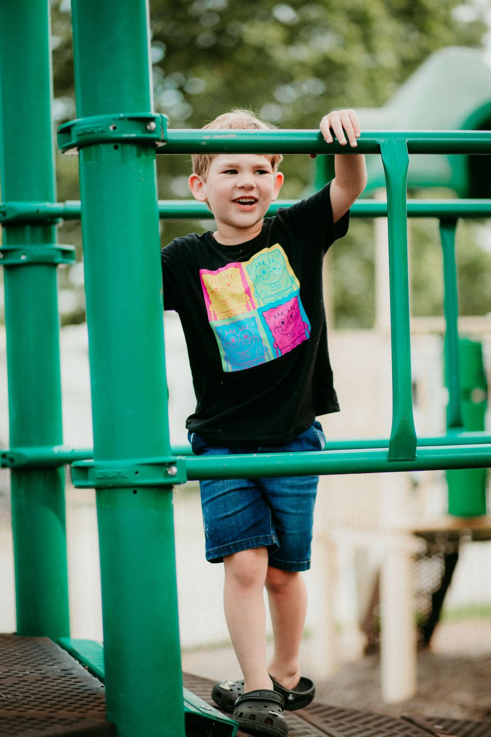 Close-up view of playground equipment showing bright green monkey bars and a child climbing through the bars.