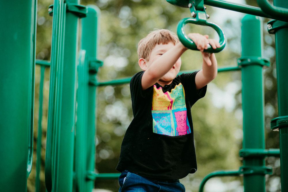 Three outdoor fitness stations with green metal equipment for performing bodyweight exercises in a park or exercise area.