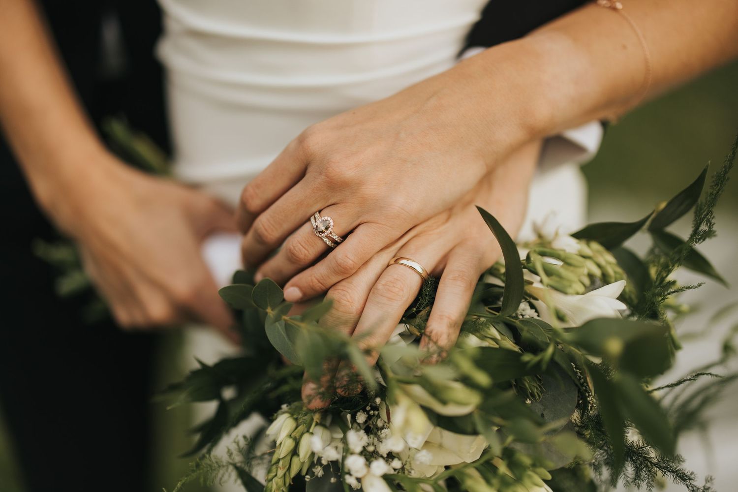 A bride and groom walking and laughing together in a garden with rustic brick walls in the background.
